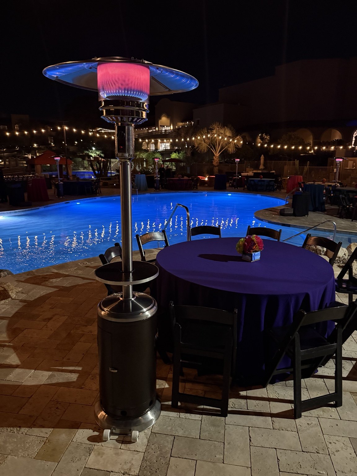 Patio heater beside an illuminated pool at night